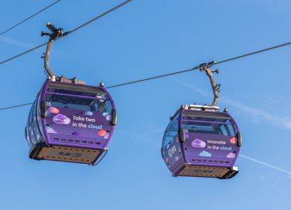 Due cabine della funivia viaggiano sopra il Tamigi sotto il cielo azzurro.