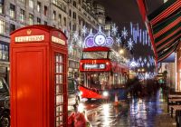 Una cabina telefonica rossa e un autobus londinese circondati dalle luminarie natalizie.