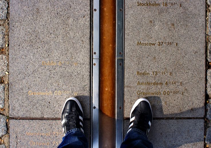 Visitatori con i piedi ai due lati del Meridiano Zero di Greenwich.