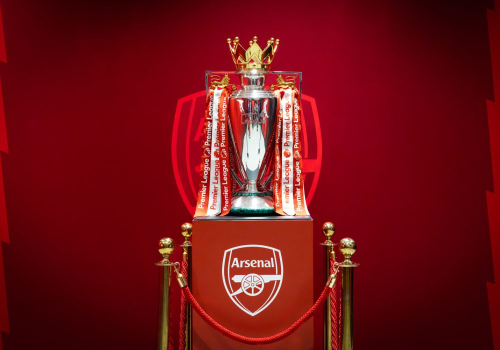Il trofeo della Premier League esposto insieme allo stemma dell’Arsenal.