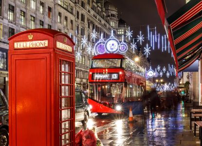 Una cabina telefonica rossa e un autobus londinese circondati dalle luminarie natalizie.