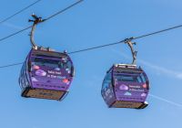 Due cabine della funivia viaggiano sopra il Tamigi sotto il cielo azzurro.