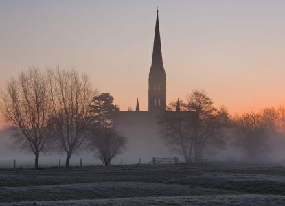La guglia della cattedrale di Salisbury sopra la nebbia invernale all'alba