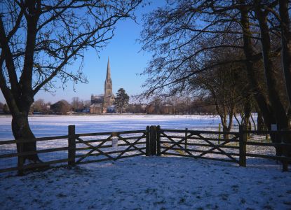 Vista della Cattedrale di Salisbury attraverso il parco ricoperto di neve.