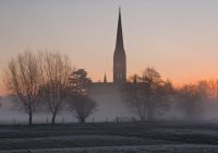 La guglia della cattedrale di Salisbury sopra la nebbia invernale all'alba